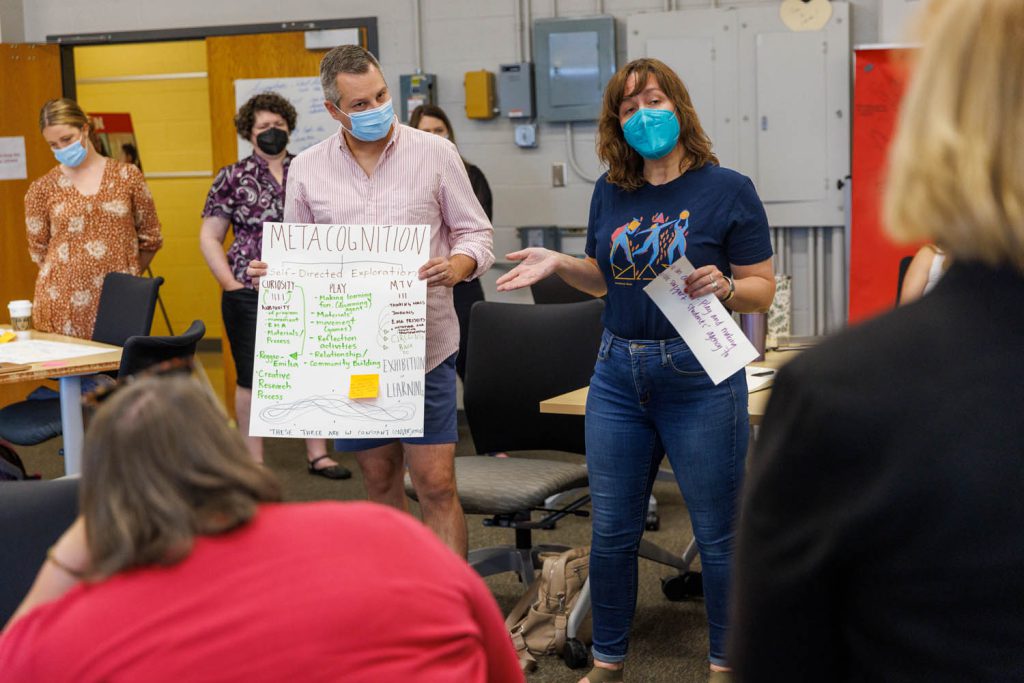 A classroom with two teachers wearing masks, talking to students