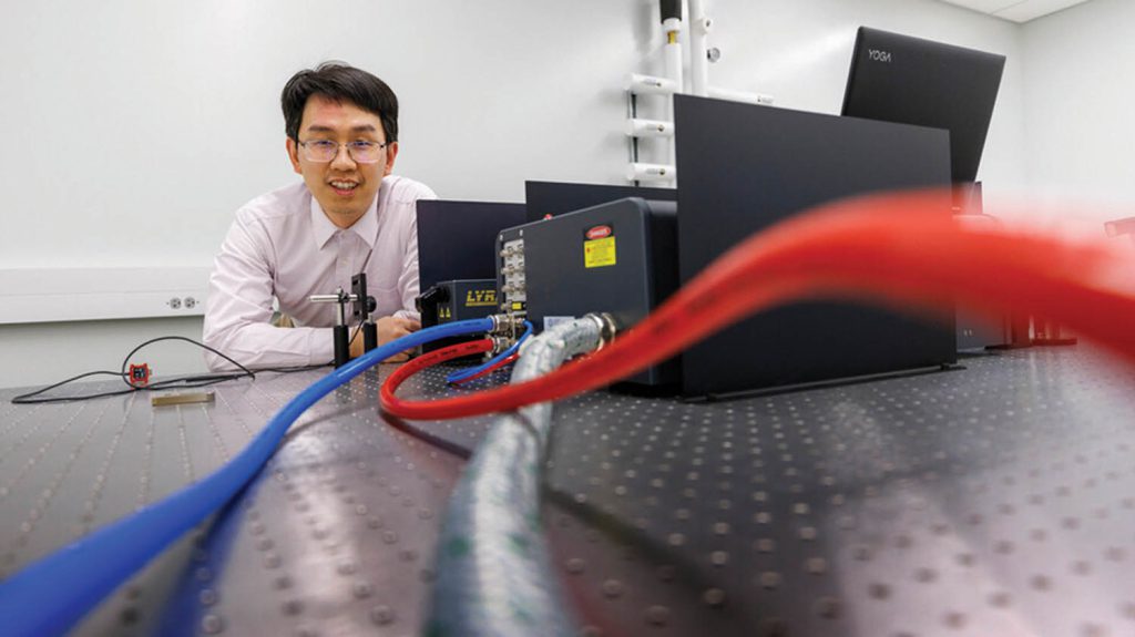 Wei Bao behind a device with red and blue wires