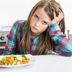 lovely girl showing boring expression with fresh colorful vegetables