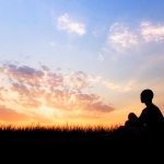 stock photo of person sitting in field against sky