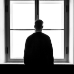 photo illustration of man looking out window