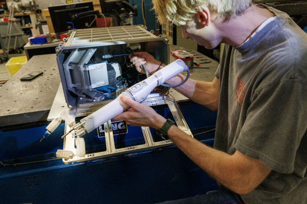 Engineering student loading robotic arm into its case 