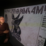 Peter Revesz in front of artwork of ancient sphinx artifact and inscription